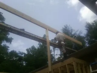 Carpenter setting a ridge beam over a new addition frame — Ice Dam Removal by Roofing Brothers in Slickville