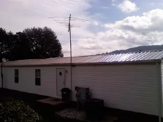 New metal roof on a single wide mobile home with a TV antenna in Slickville