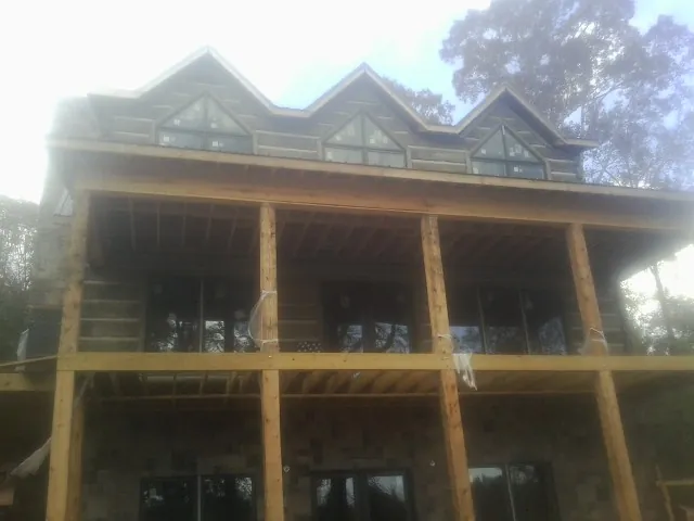 Dormers and porch framing on a large log home under construction — Roof Coating work by our crew in Slickville