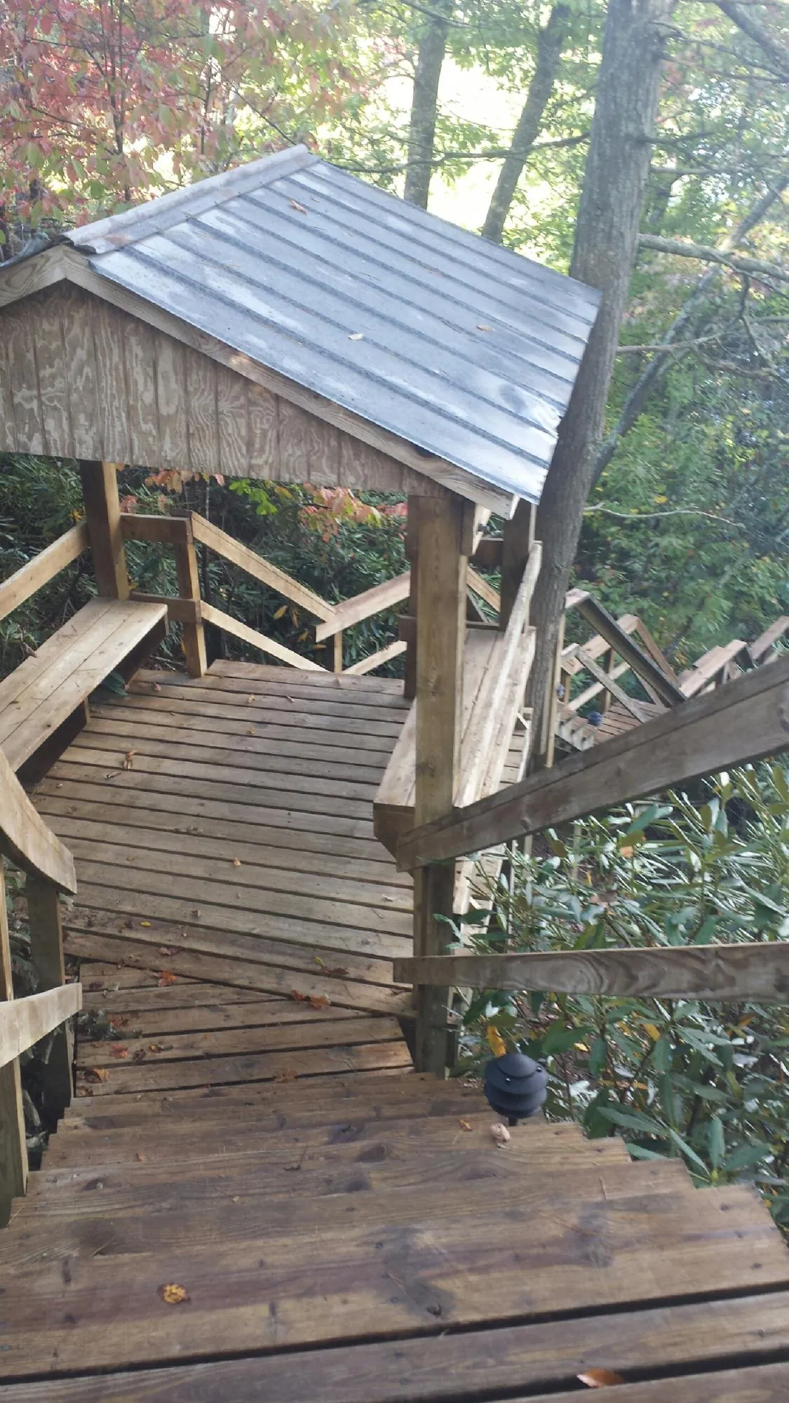 Metal roofed shelter over wooden steps on a wooded walkway — Skylight Repair & Installation work by our crew in Slickville