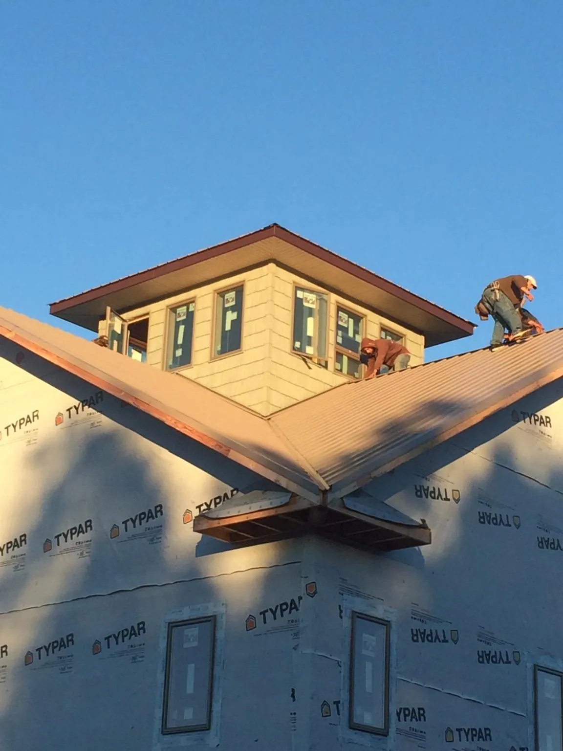 Roofers working around a rooftop cupola on a new metal roof at sunset — Roof Waterproofing in Slickville by Roofing Brothers